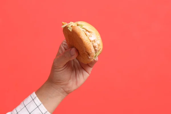 Azjata Trzyma Hamburgera Pomarańczowym Tle — Zdjęcie stockowe