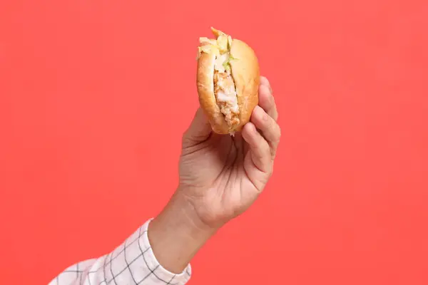 Tangan Pria Asia Memegang Hamburger Latar Belakang Oranye — Stok Foto