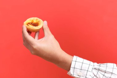 Turuncu arka planda yumurtalı tart tutan Asyalı adam..