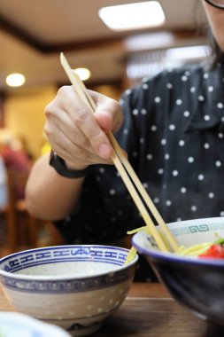 Restoranda ramen yiyen Asyalı kadın..