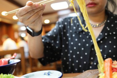 Restoranda ramen yiyen Asyalı kadın..