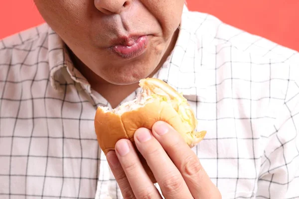Pria Asia Makan Hamburger Latar Belakang Oranye — Stok Foto