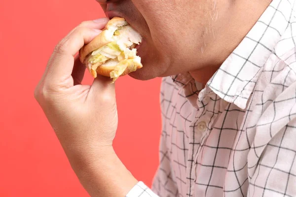 Uomo Asiatico Mangiare Hamburger Sullo Sfondo Arancione — Foto Stock