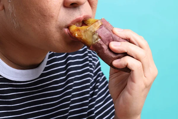 Uomo Asiatico Mangiare Patate Dolci Sullo Sfondo Verde — Foto Stock