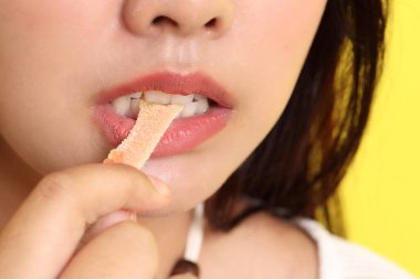 Sarı arka planda jöle yiyen Asyalı kadın..