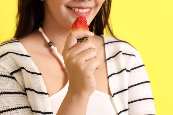 Die Asiatin Isst Erdbeere Aus Der Hand Auf Gelbem Hintergrund — Stockfoto