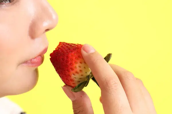 Die Asiatin Isst Erdbeere Aus Der Hand Auf Gelbem Hintergrund — Stockfoto