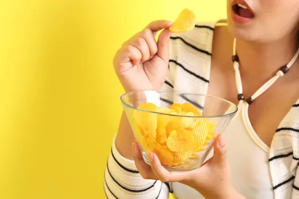Die Asiatin Isst Kartoffelchips Aus Der Hand Auf Gelbem Hintergrund — Stockfoto