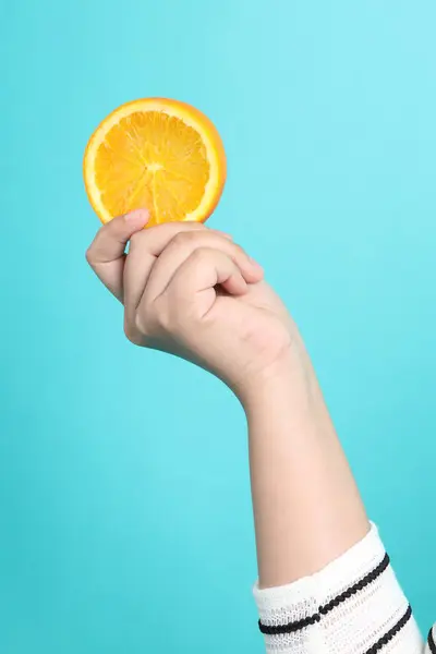 The Asian woman holding orange in the hand on the green background.