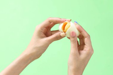 Yeşil arka planda elinde yumurta tutan Asyalı kadın..