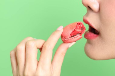 Sarı arka planda elden badem kurabiyesi yiyen Asyalı kadın..