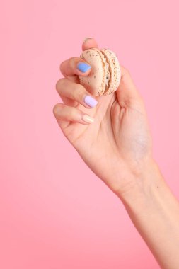 Pembe arka planda elinde kurabiye tutan Asyalı kadın..