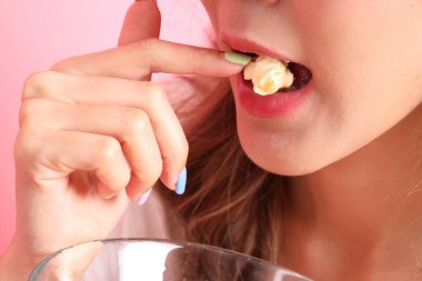 Pembe arka plandaki elden patlamış mısır yiyen Asyalı kadın..