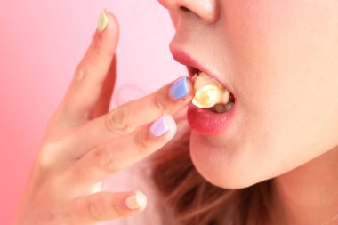 Pembe arka plandaki elden patlamış mısır yiyen Asyalı kadın..