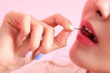 Pembe arka planda elinden meyve yiyen Asyalı kadın..