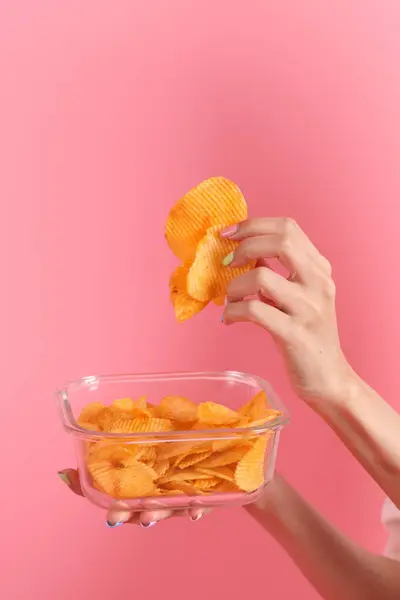 Aziatische Vrouw Eten Aardappel Chips Uit Hand Roze Achtergrond — Stockfoto