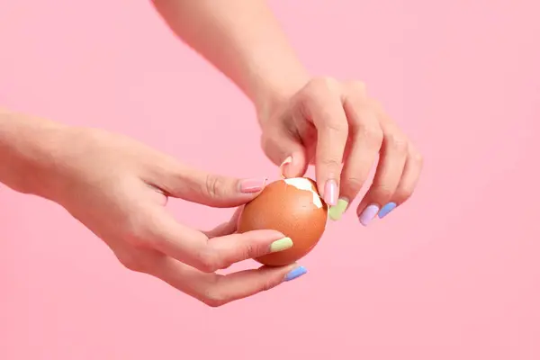The Asian woman eating egg in the hand on the green background.