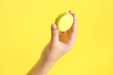 Sarı arka planda elden badem kurabiyesi yiyen Asyalı kadın..