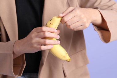 Mor arka plandaki elden muz yiyen Asyalı kadın..