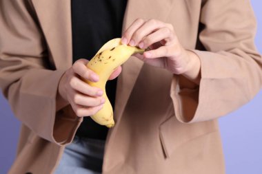 Mor arka plandaki elden muz yiyen Asyalı kadın..