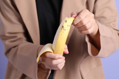 Mor arka plandaki elden muz yiyen Asyalı kadın..