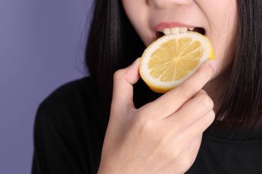 Mor arka planda limon tutan Asyalı kadın..