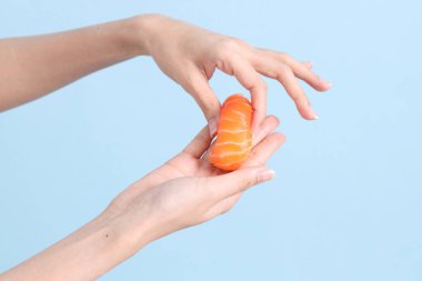 Mavi arka planda sushi tutan Asyalı kadın..