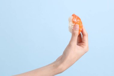 Mavi arka planda sushi tutan Asyalı kadın..