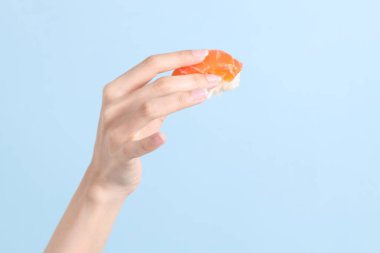 Mavi arka planda sushi tutan Asyalı kadın..