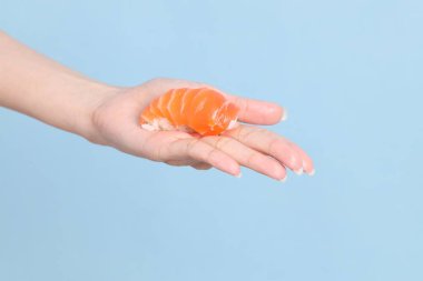 Mavi arka planda sushi tutan Asyalı kadın..