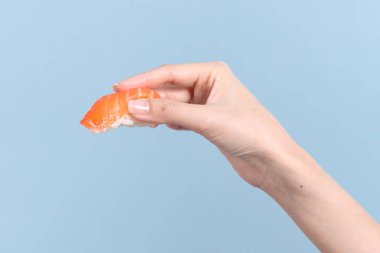 Mavi arka planda sushi tutan Asyalı kadın..