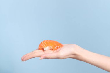 Mavi arka planda sushi tutan Asyalı kadın..