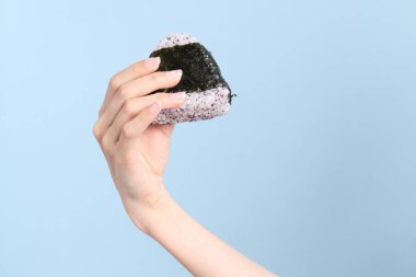 Mavi arka planda onigiri tutan Asyalı kadın..