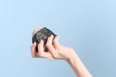 Mavi arka planda onigiri tutan Asyalı kadın..