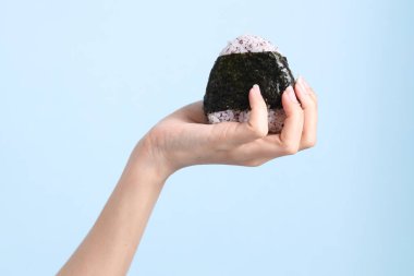 Mavi arka planda onigiri tutan Asyalı kadın..