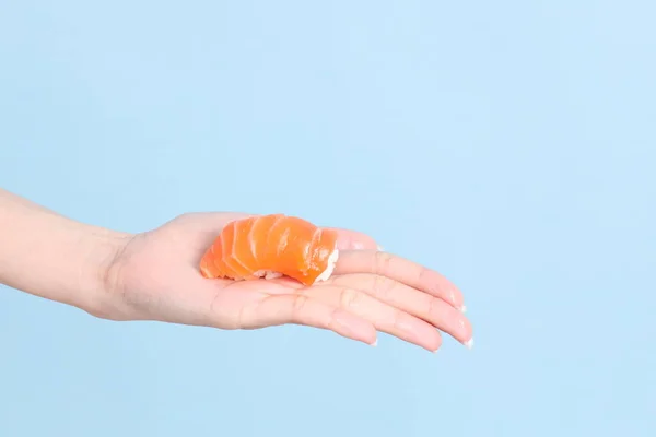 stock image The Asian woman hand holding sushi in the blue background.