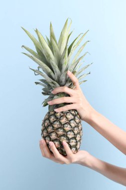 Mavi arka planda ananas tutan Asyalı kadın..