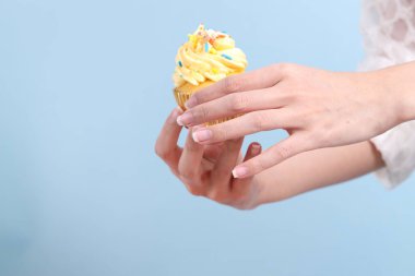 Mavi arka planda kek yiyen Asyalı kadın..