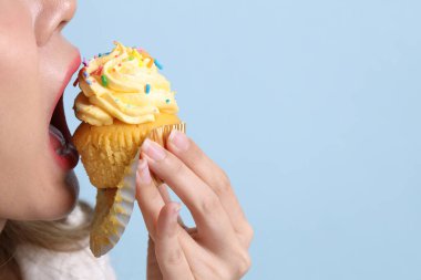 Mavi arka planda kek yiyen Asyalı kadın..