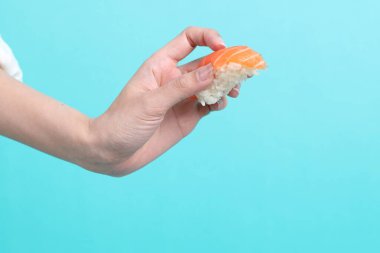 Yeşil arka planda suşi tutan Asyalı kadın..