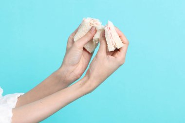 Mavi arka planda sandviç yiyen Asyalı kadın..