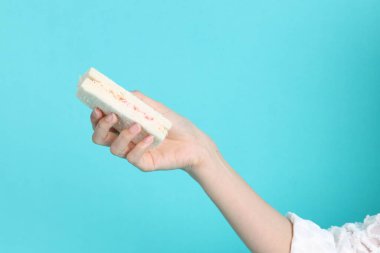 Mavi arka planda sandviç yiyen Asyalı kadın..