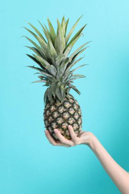 Yeşil arka planda ananas tutan Asyalı kadın..