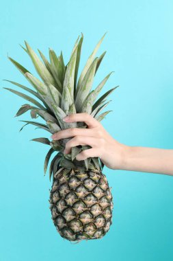 Yeşil arka planda ananas tutan Asyalı kadın..