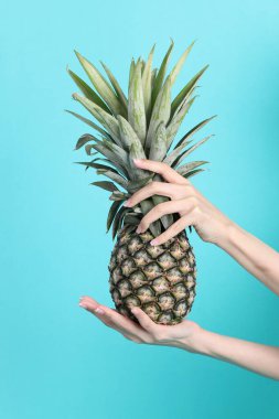 Yeşil arka planda ananas tutan Asyalı kadın..