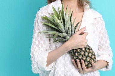 Yeşil arka planda ananas tutan Asyalı kadın..