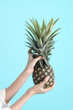 Yeşil arka planda ananas tutan Asyalı kadın..