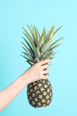 Yeşil arka planda ananas tutan Asyalı kadın..