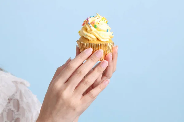 The Asian woman eating cupcakes on the blue background.