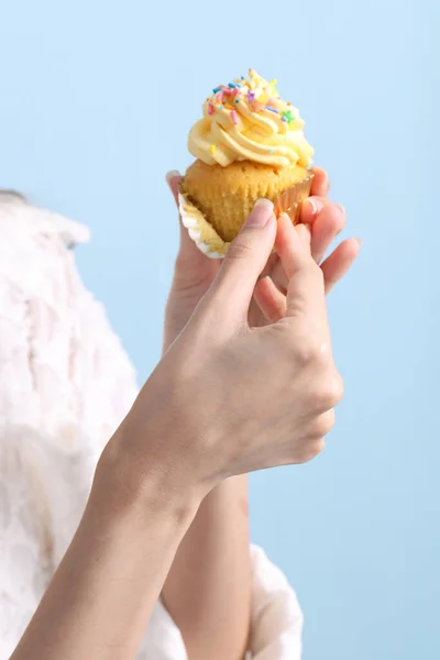 The Asian woman eating cupcakes on the blue background.